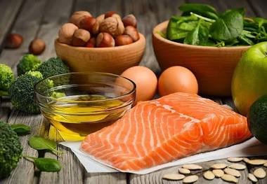 A spread of fresh salmon, olive oil, broccoli, and nuts representing a fatty liver diet.